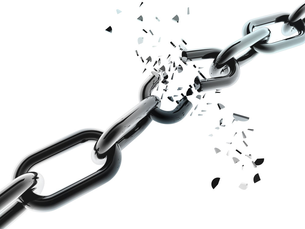 Close-up of a black metal chain with one link breaking apart, surrounded by scattered fragments against a white background.