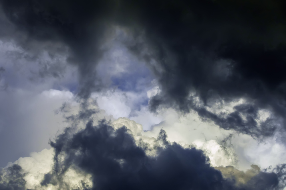 Dark storm clouds fill the sky, with a few patches of lighter clouds and hints of blue peeking through.