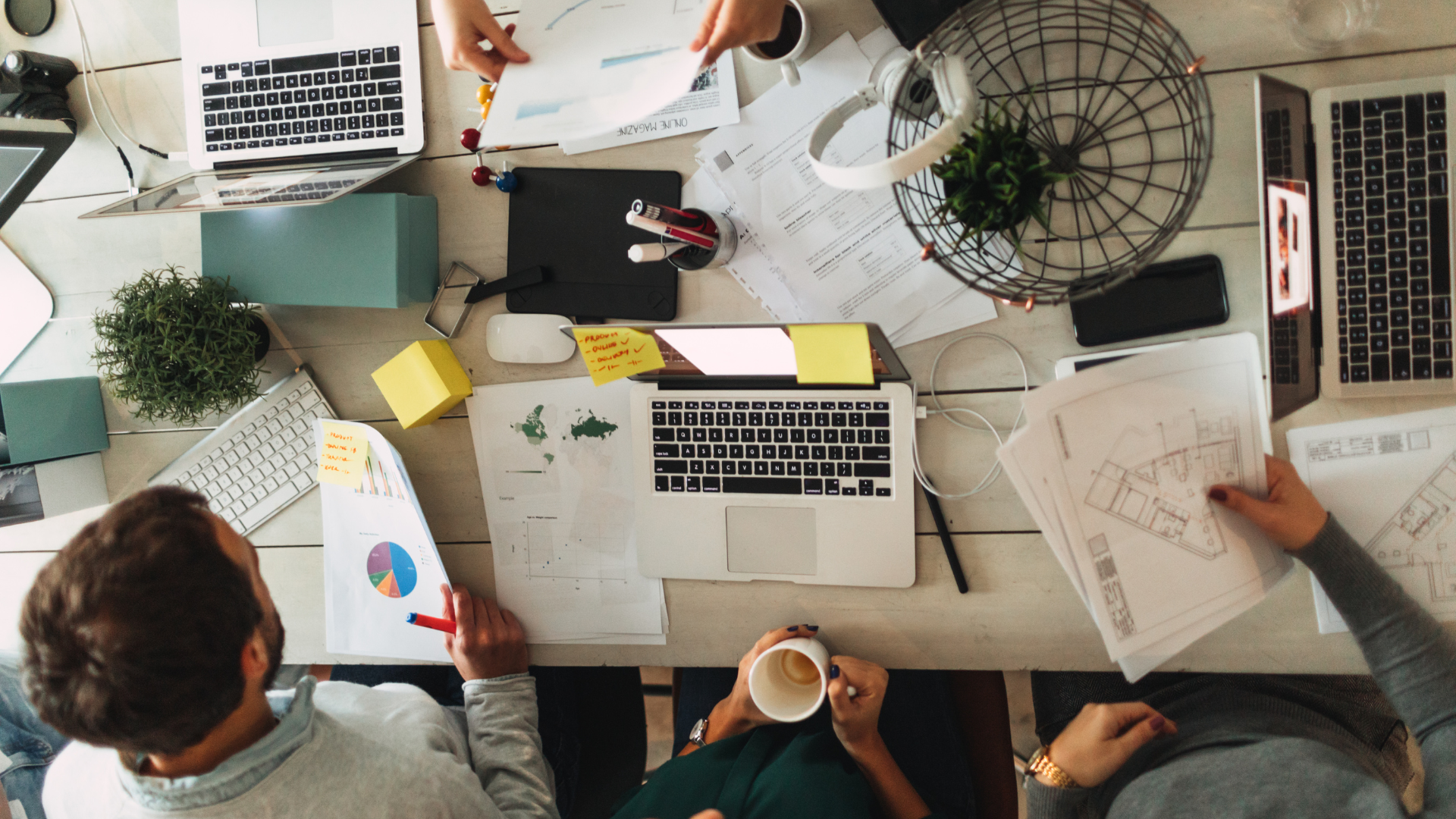 A group of people working at a cluttered desk with laptops meticulously collaborating on Bankruptcy Restructuring Services.