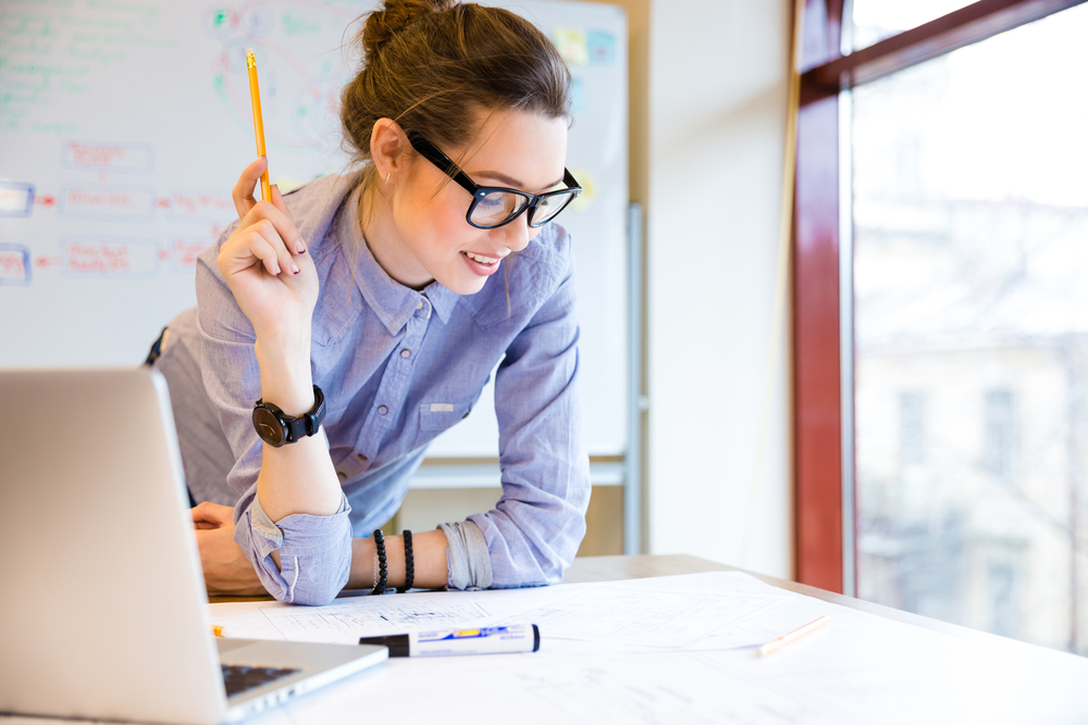 A woman in glasses looking at papers related to insurance and risk management.