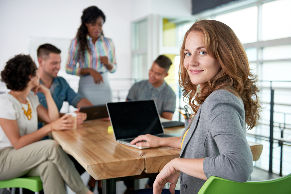 A woman with curly hair and a gray blazer, possibly from one of Florida's top risk advisory firms, is sitting in the foreground, looking at the camera.