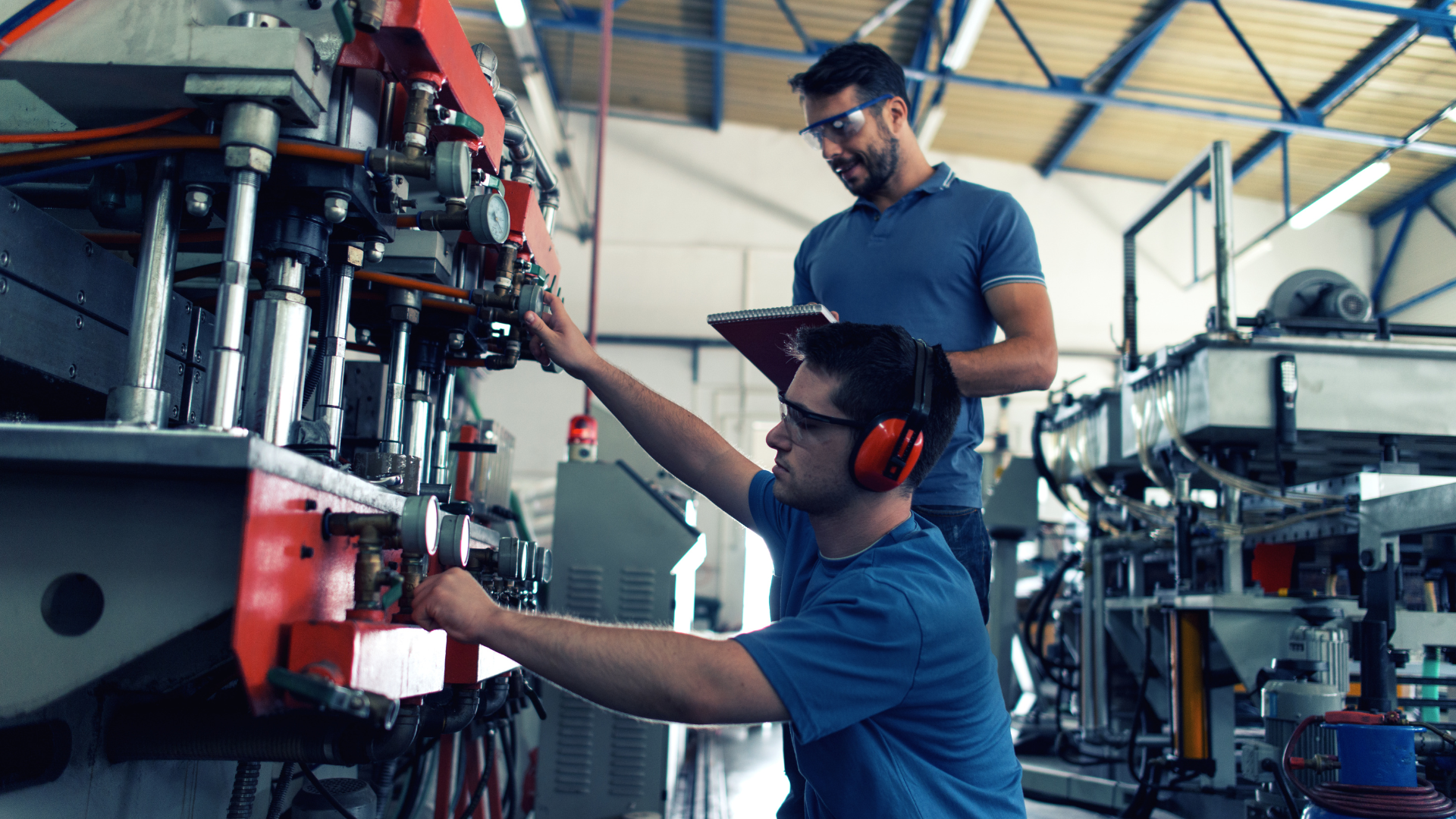 Two men working in a manufacturing and distribution facility, both dressed in blue shirts.