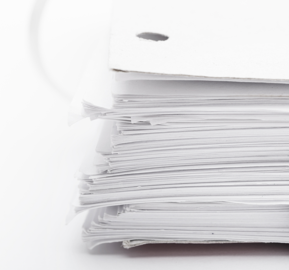 A stack of white paper sheets with holes punched in the top left corner, placed against a white background.