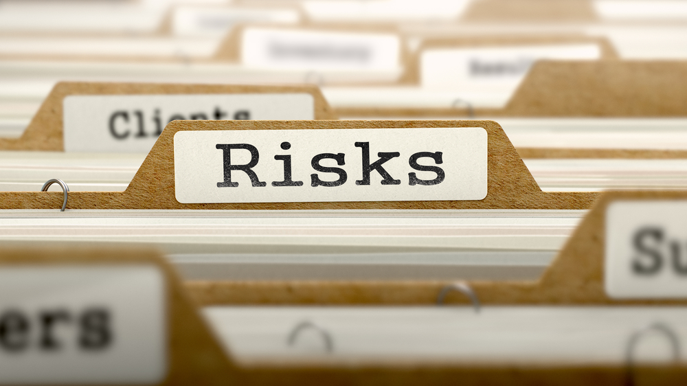 Close-up of a file tab labeled "Risks" in a filing system, highlighting the importance of risk management services.