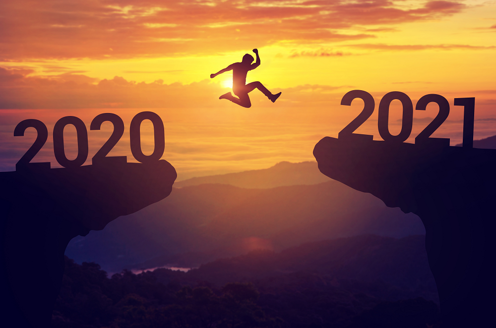 A person is silhouetted against a sunset, leaping from a cliff symbolizing the transition from one year to the next with a sense of risk management.