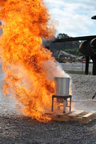 A column of flames rises from a metal container on a stand