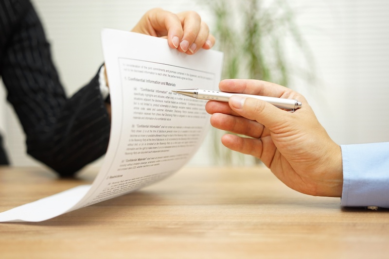 One person hands an insurance contract highlighting the importance of risk management.