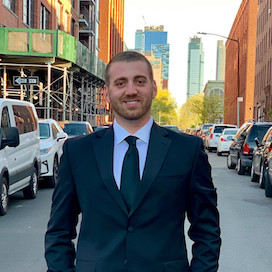 A certified risk management consultant wearing a black suit and tie stands on a bustling city street