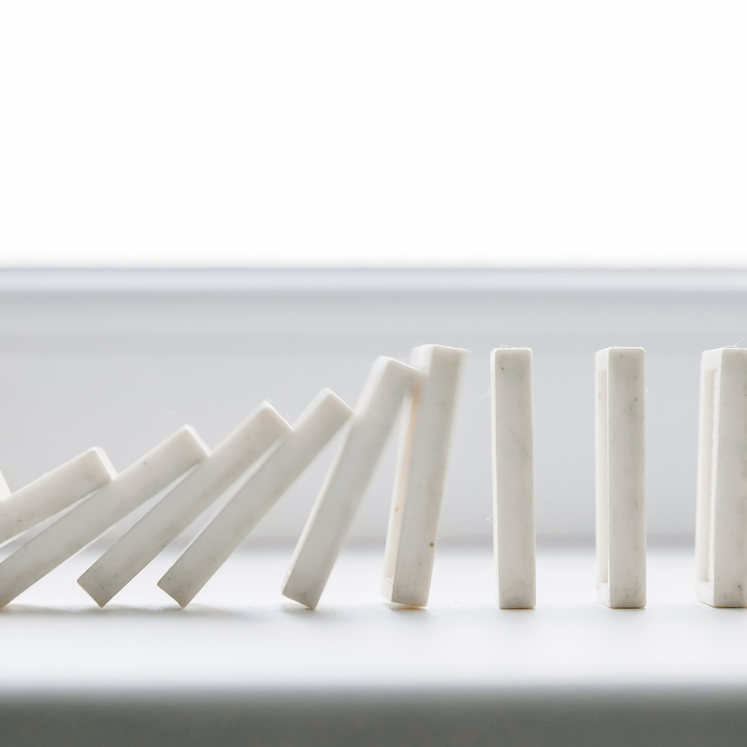 White domino tiles standing upright, placed on a smooth white surface, symbolizing the delicate balance of corporate principles.