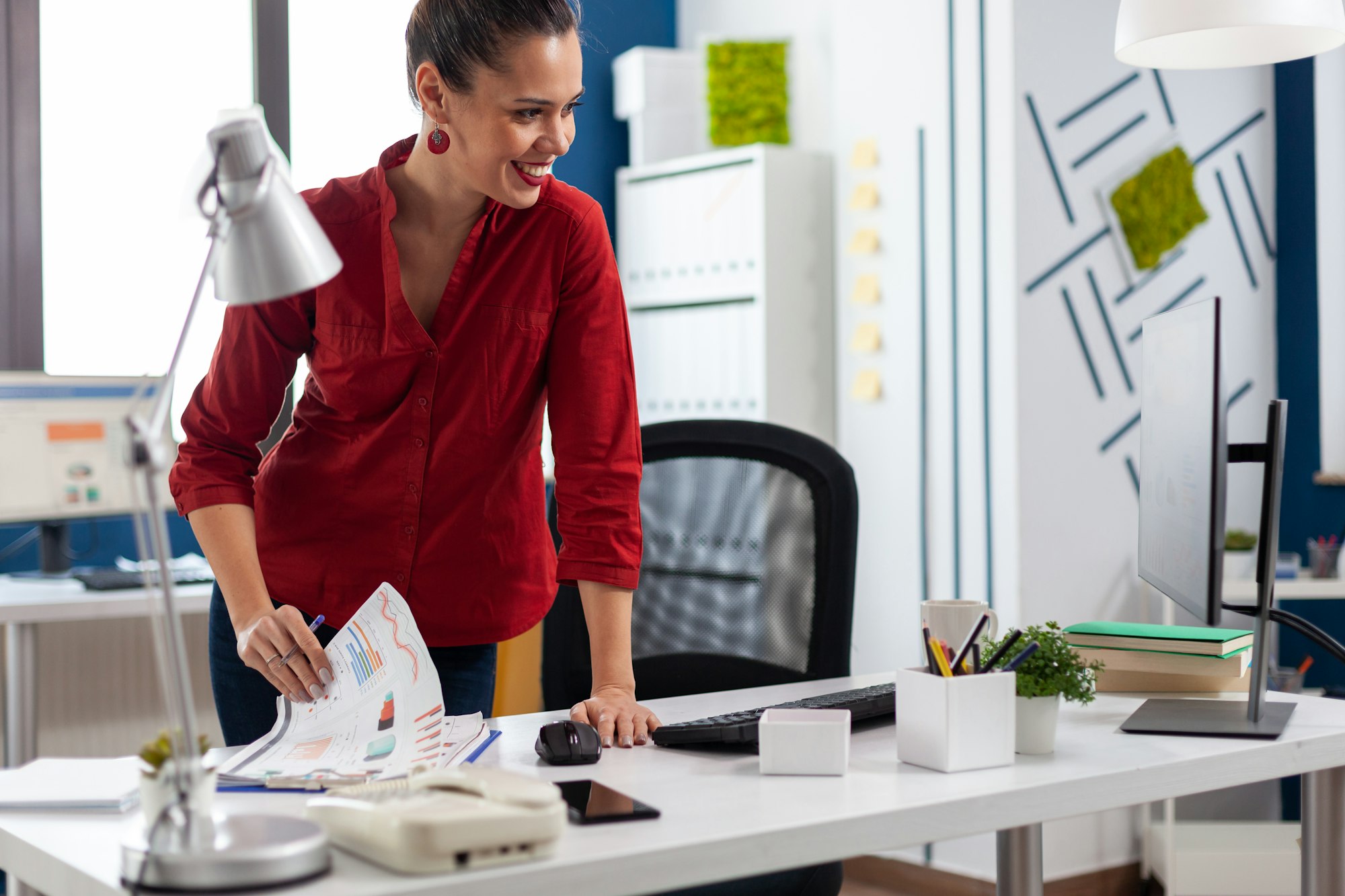 Standing businesswoman in company office reading official document