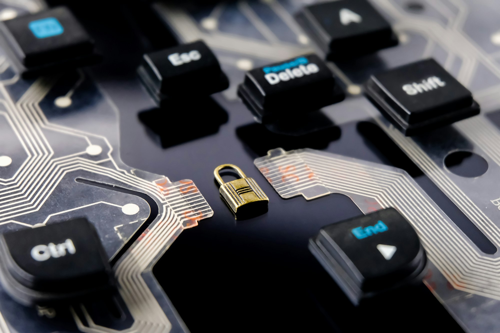 Close-up of a computer keyboard's internal circuit board with a small padlock placed on it, surrounded by visible keys like Ctrl, Shift, Esc, Delete, and End—symbolizing the importance of cyber risk assessment.