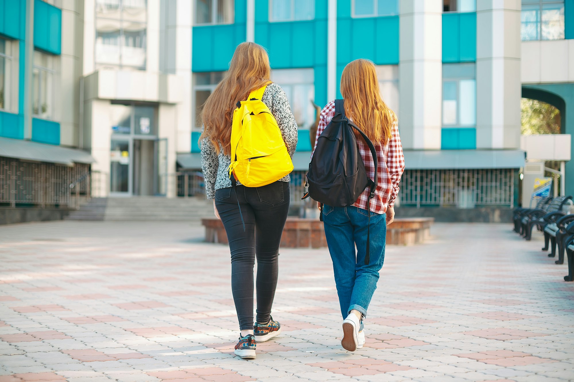 Young college girl friends, with natural reddish hair, going to