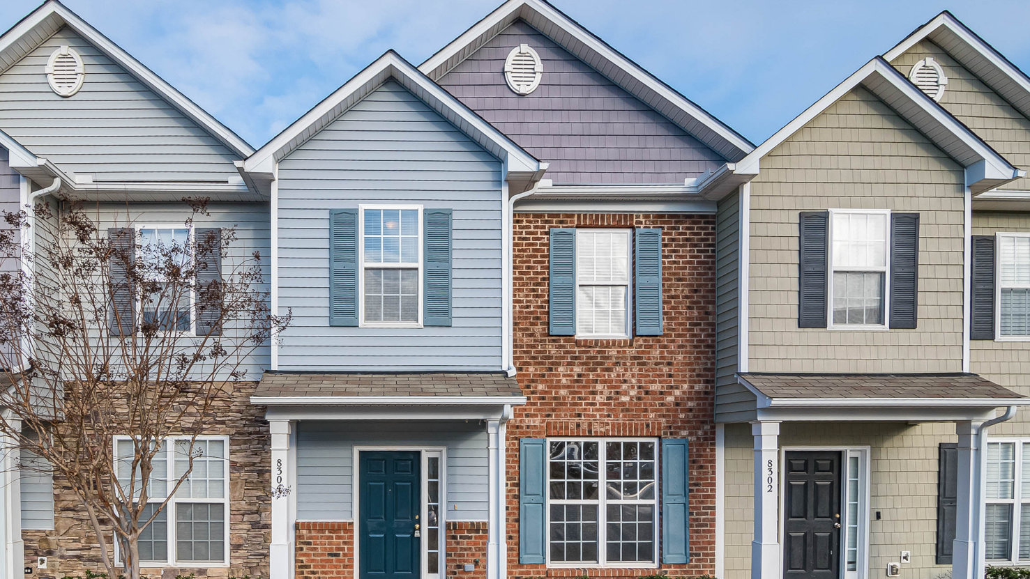 A row of three townhouses with varied exterior siding and colorful doors.
